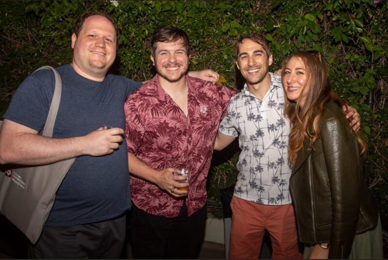 Four people smile for a photo at a party