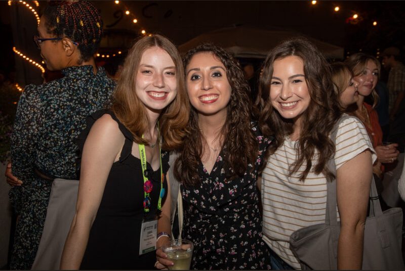 Three people smile for a photo at a party