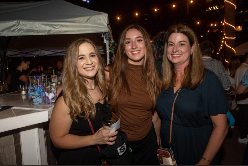 Three people smile for a photo at a party