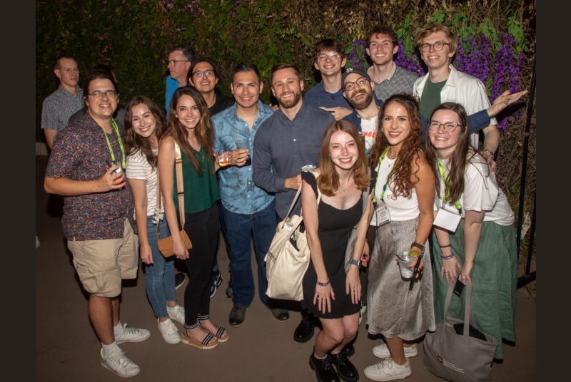 Thirteen people smile for a photo at a party