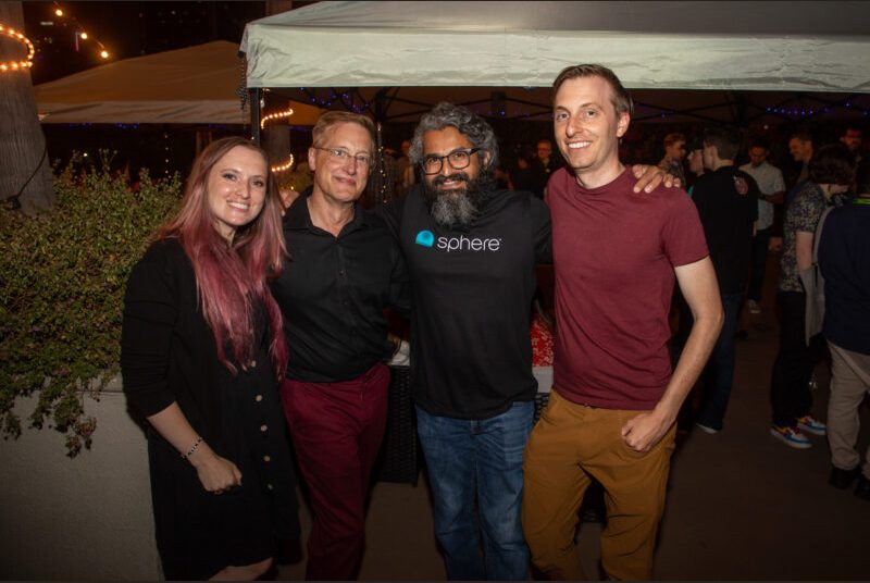 Four people smile for a photo at a party