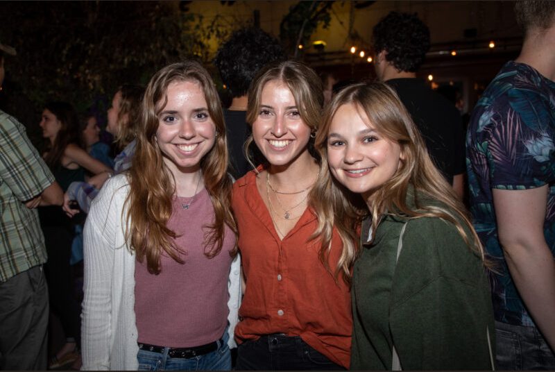 Three people smile for a photo at a party