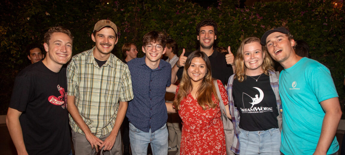 Seven people smile for a photo at a party.