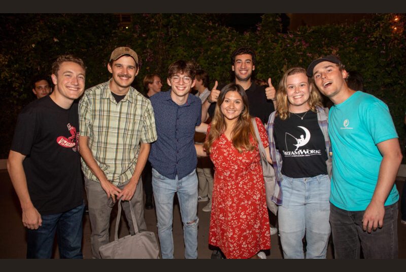 Seven people smile for a photo at a party.