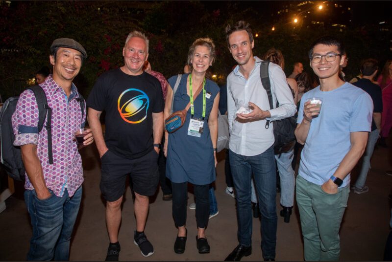 Five people smile for a photo at a party