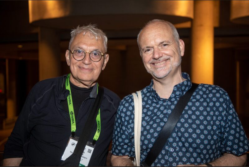 Two men stand and smile for a photo