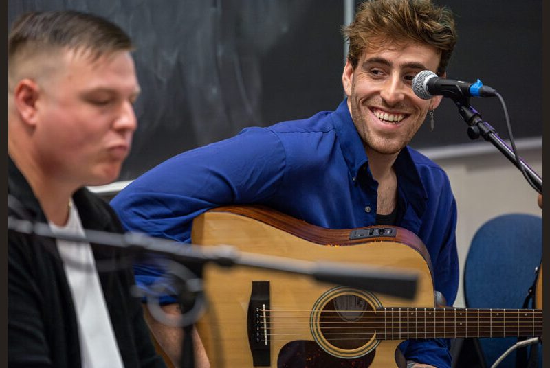 A rock group performs for college students in a classroom.