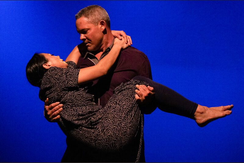 Two dancers perform, one cradling the other in his arms.