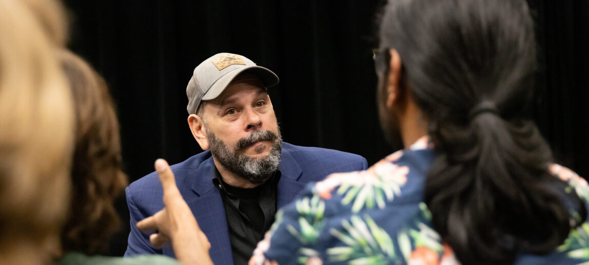 A view of a discussion between a college student and an improv performer at an improv-comedy workshop.