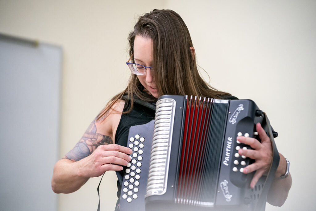A college professor plays an accordion in a classroom setting.