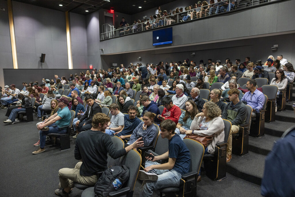 A crowd gathers in a screening room.