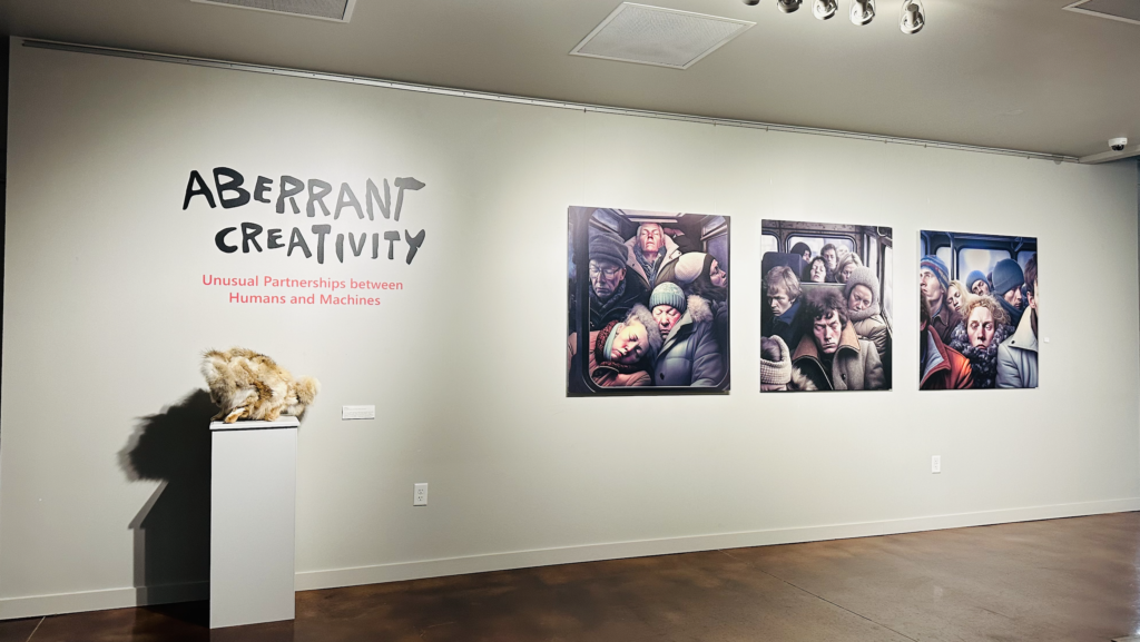 A wall of an art exhibition shows the words "Aberrant Creativity: Unusual Partnerships between Humans and Machines." Three images of people on a crowded bus or subway are posted on the wall. Another art piece that resembles an animal's fur is on a pedestal.