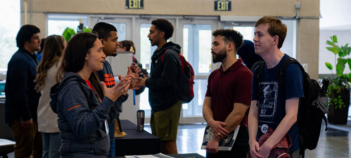 A professional in the video game industry talks with a college student at a job fair.