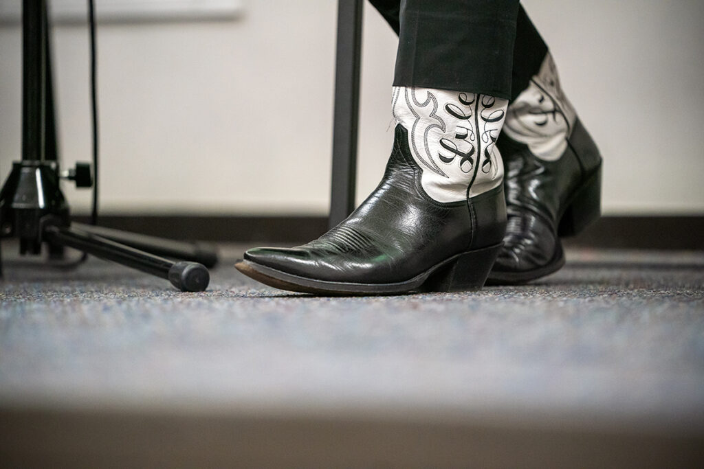 Lyle Lovett's black-and-white boots are pictured, with the word "Lyle" visible.