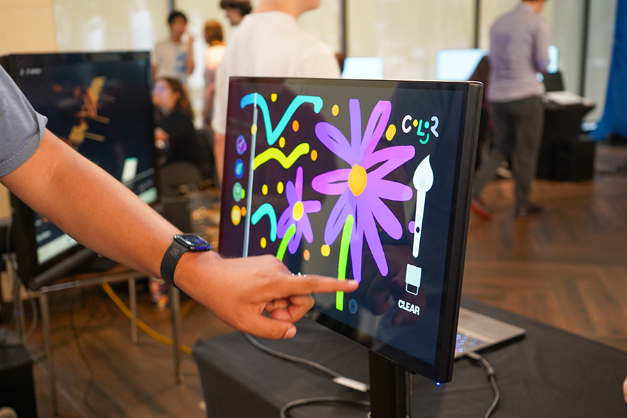 A college student interacts with a touch screen, with flower designs on the screen.