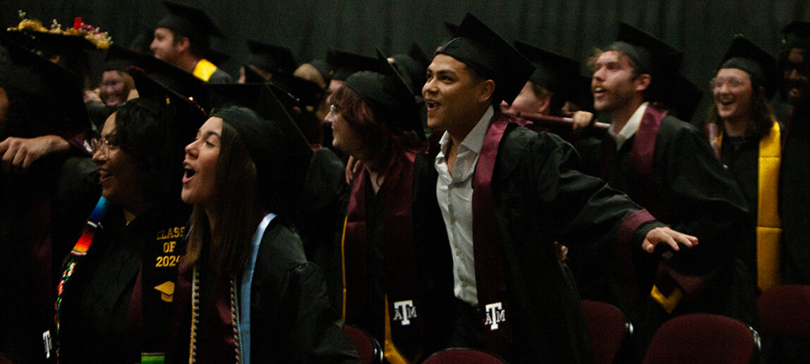 A group of college students in traditional caps and gowns celebrate at a graduation ceremony.