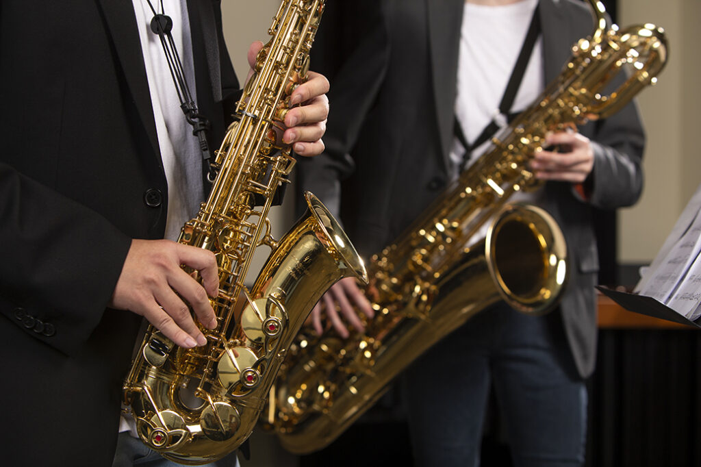 A closeup of two students performing with saxophones.