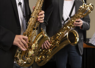 A closeup of two students performing with saxophones.