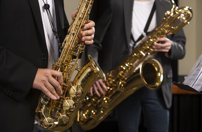 A closeup of two students performing with saxophones.