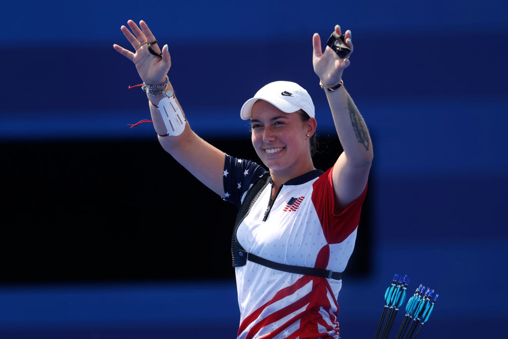 An Olympic archer raises her hands in victory and smiles at the Olympic Games in Paris.