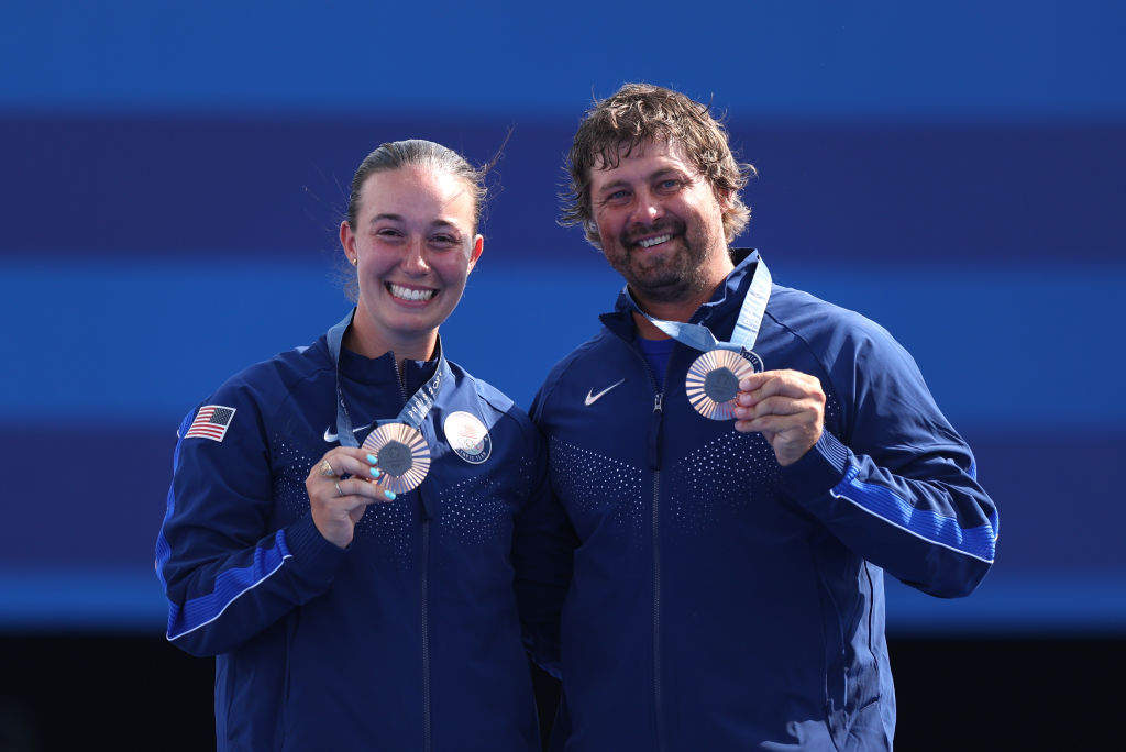 Two Olympic archers hold their bronze medals and smile at the Olympic Games in Paris.