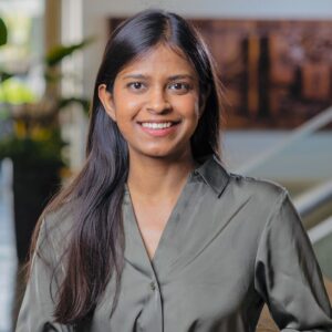 A portrait of a woman smiling in an academic building's atrium.