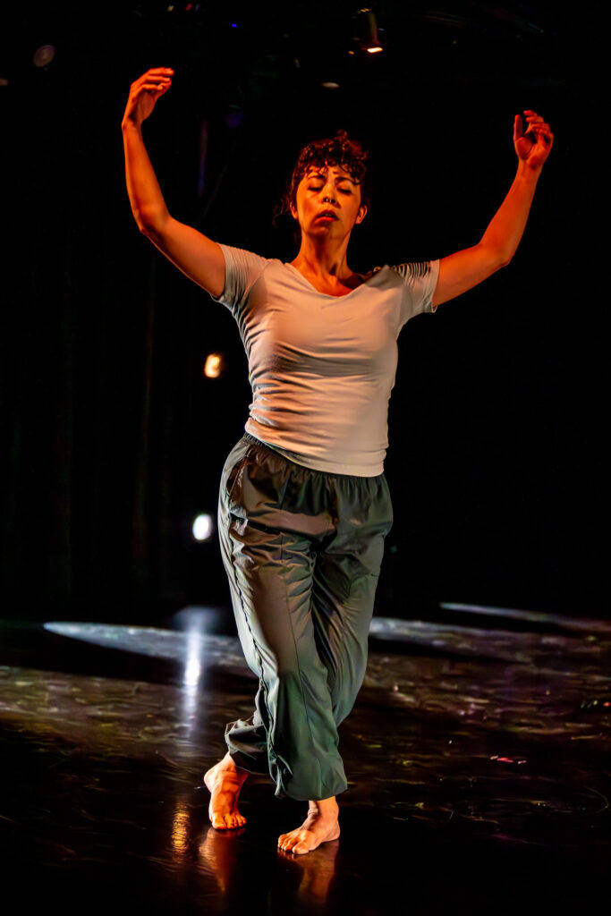 A dance professor performs in a darkened black box theater.