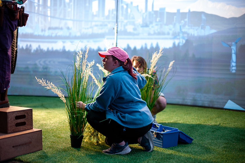 Two college students work with plant props for a short film being shot on a virtual production stage.