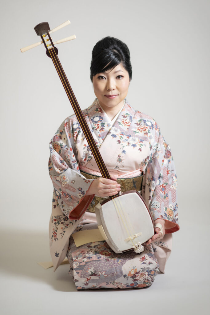 A musician poses with an ancient Japanese stringed instrument.