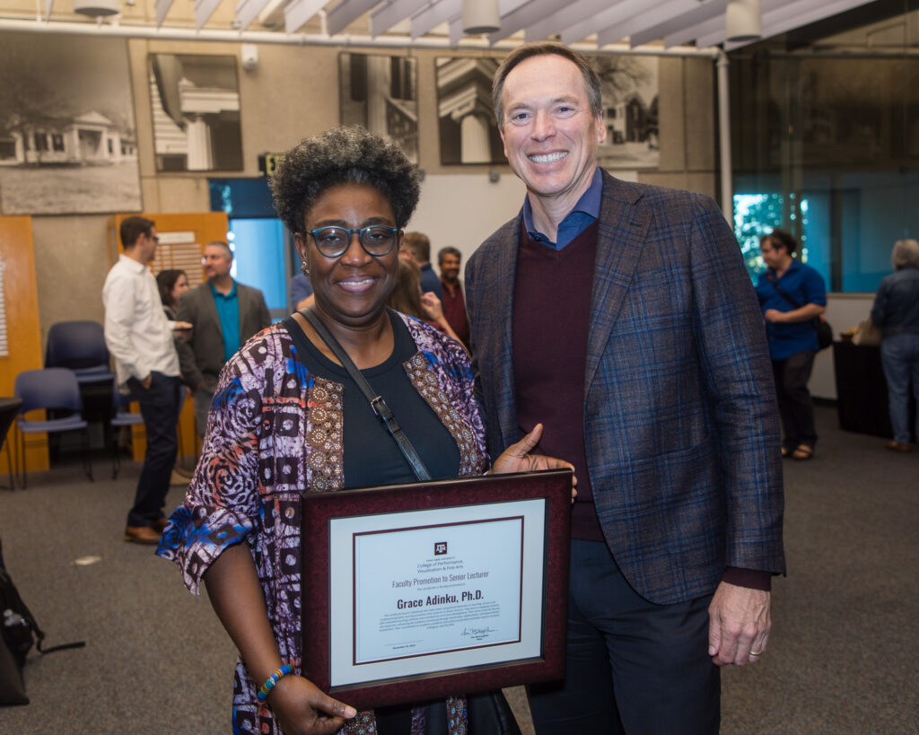 A woman holds a framed certificate of achievement. To her left is a university dean.