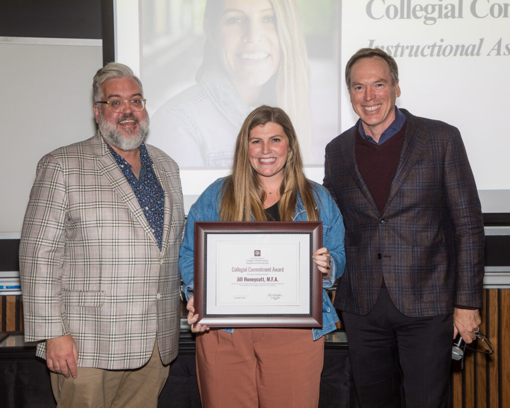 A woman holds a framed certificate of achievement. Two university leaders stand alongside her.