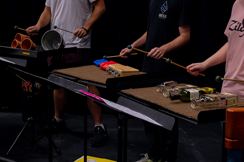 A close-up view of nontraditional instruments — flowerpots and bottles — during a percussion concert.