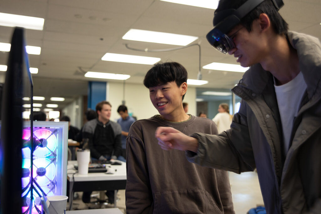 Two college students engage with a virtual reality demonstration.