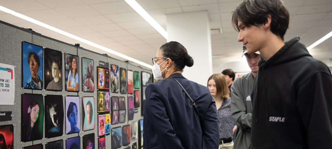 People view artwork as part of a student showcase.