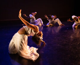 Dancers perform in a variety of poses on a stage.