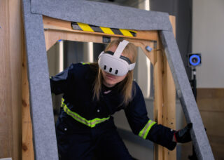 A student wears an augmented reality headset device as he steps through a simulated environment.