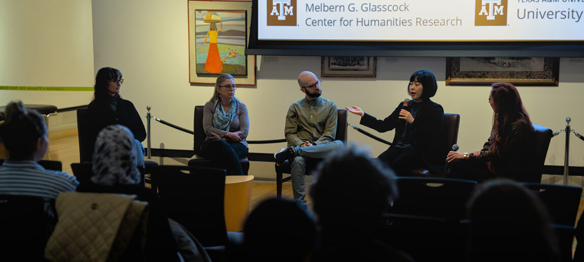 Five university professors are seated as they have a discussion in an art gallery event.