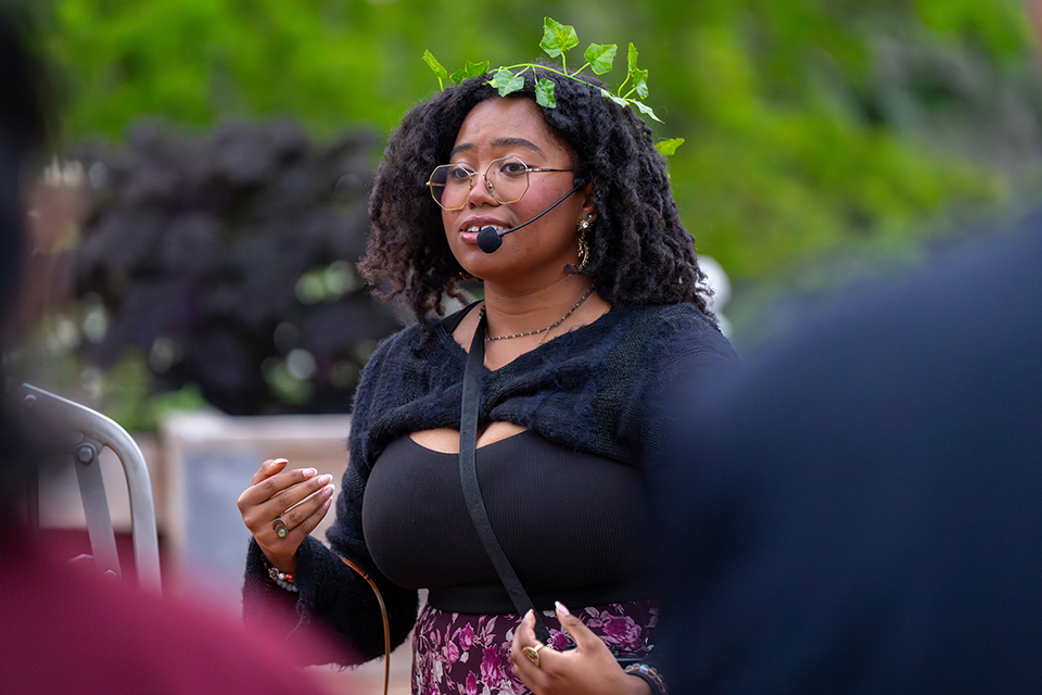 A student wearing a leafy crown speaks into a headset microphone.