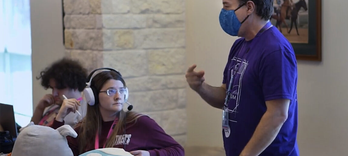 Someone instructs a student working at a computer